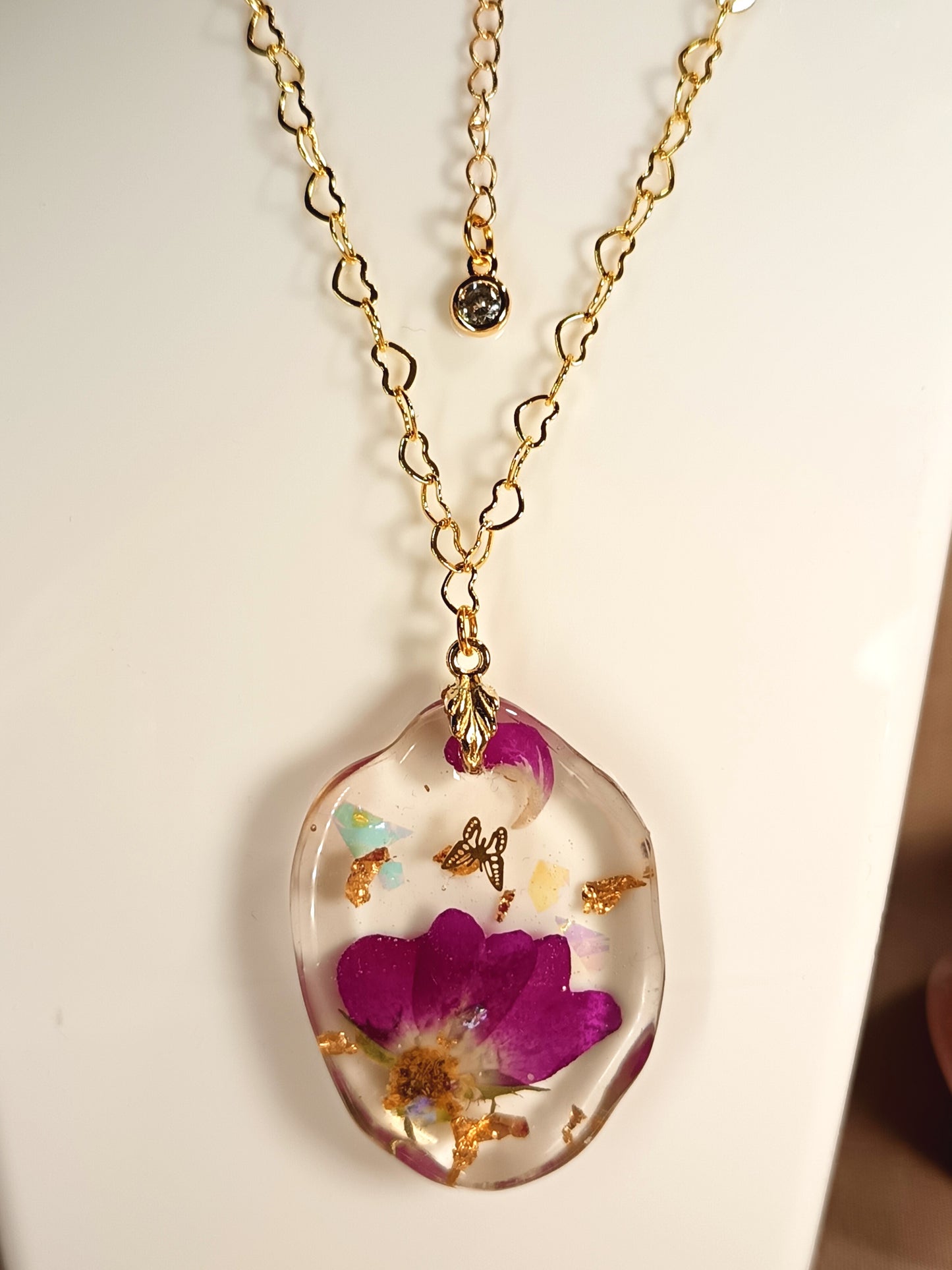 Dettaglio collana artigianale con fiore viola e catena dorata