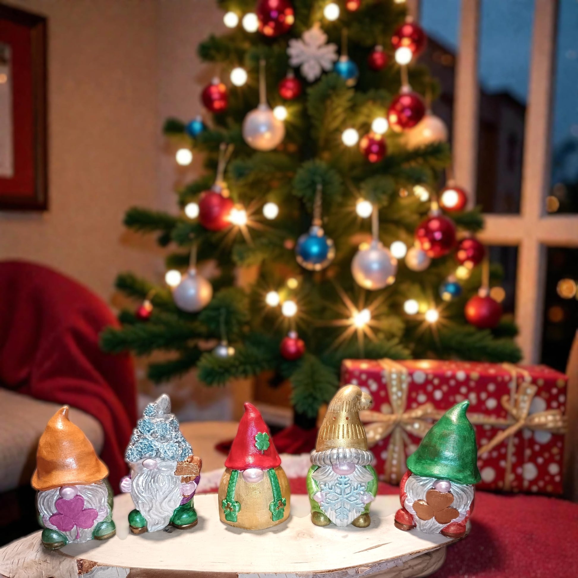 Gnomi natalizi artigianali in gesso con colori metallizzati davanti albero di natale